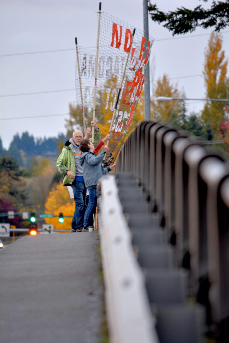Two activists stand on a bridge holding a banner