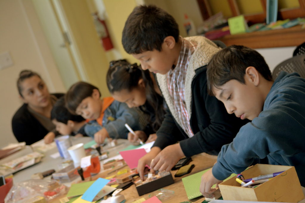 Children seated at a table creating cards